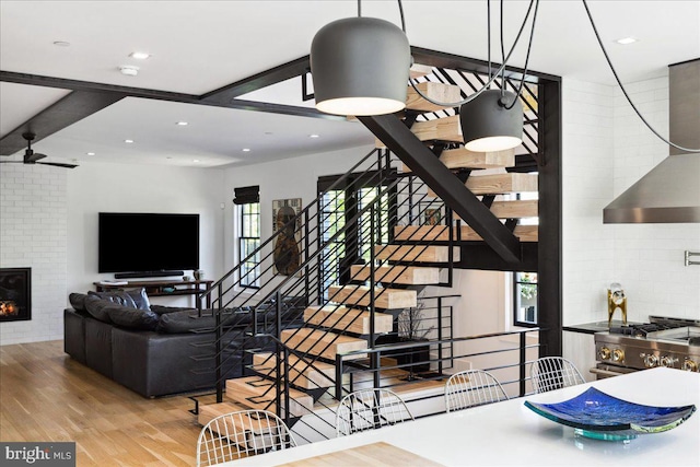 living area featuring stairs, recessed lighting, wood finished floors, and a fireplace