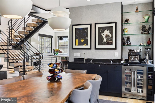 dining area with stairs, beverage cooler, wet bar, and light wood-style flooring