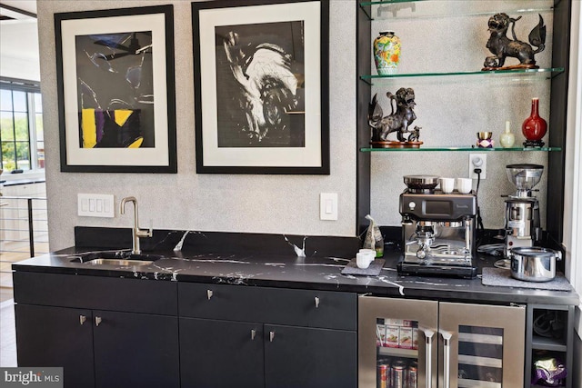 bar featuring a sink, wet bar, a textured wall, and beverage cooler