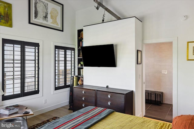 bedroom with baseboards, lofted ceiling, radiator heating unit, and wood finished floors