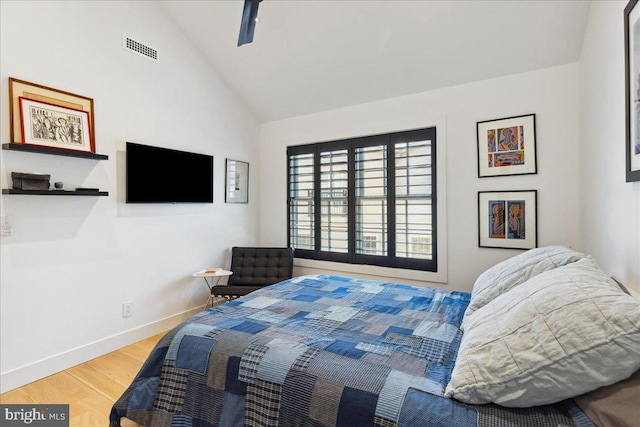 bedroom with ceiling fan, visible vents, wood finished floors, baseboards, and lofted ceiling