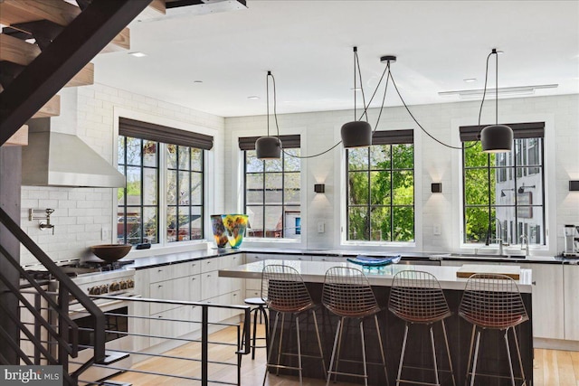 bar with light wood-type flooring, a healthy amount of sunlight, and tasteful backsplash