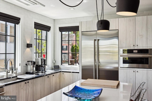 kitchen featuring a sink, light brown cabinets, modern cabinets, and stainless steel appliances