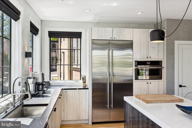 kitchen featuring light countertops, a sink, decorative light fixtures, and stainless steel appliances