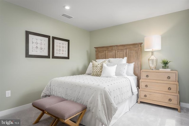 bedroom with baseboards, visible vents, and light carpet