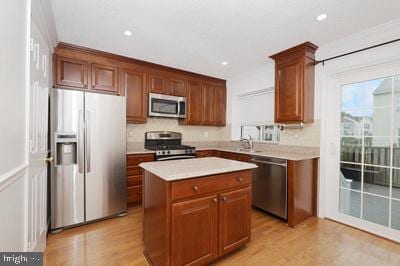 kitchen with recessed lighting, light wood finished floors, light countertops, a kitchen island, and appliances with stainless steel finishes