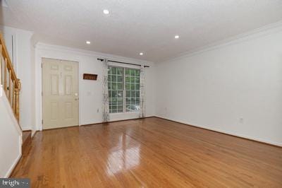 empty room with recessed lighting, stairway, crown molding, and wood finished floors
