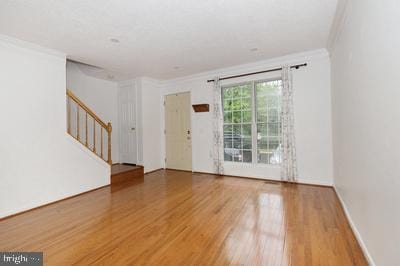 interior space with stairway, crown molding, and wood finished floors