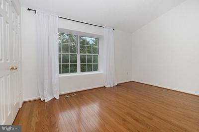 unfurnished room with lofted ceiling, baseboards, and wood finished floors