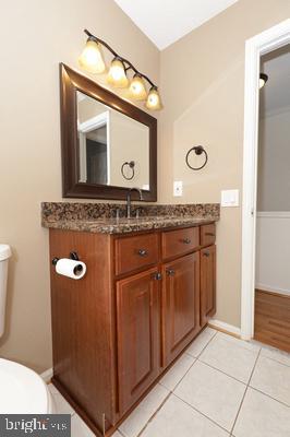 bathroom featuring tile patterned floors, toilet, baseboards, and vanity