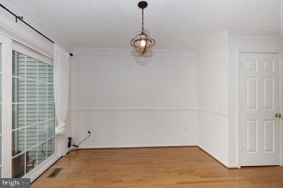 unfurnished dining area featuring crown molding, visible vents, wood finished floors, and a healthy amount of sunlight