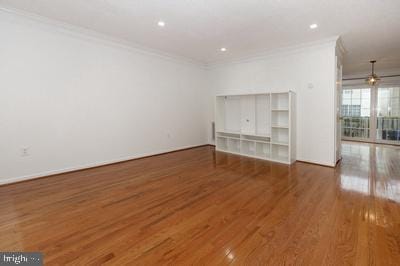empty room with baseboards, ceiling fan, crown molding, and wood finished floors