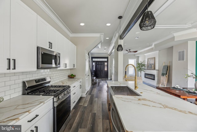 2817 Ulman Ave, Baltimore, MD 21215 - kitchen featuring appliances with stainless steel finishes, dark wood-style floors, crown molding, decorative backsplash, and a glass covered fireplace