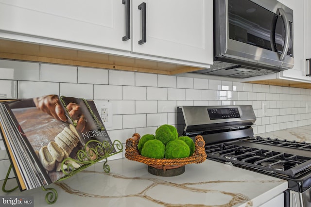 2817 Ulman Ave, Baltimore, MD 21215 - kitchen featuring stainless steel appliances, tasteful backsplash, light stone counters, and white cabinetry