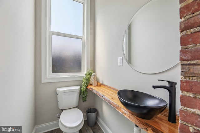 2817 Ulman Ave, Baltimore, MD 21215 - half bathroom featuring toilet, baseboards, a sink, and wood finished floors