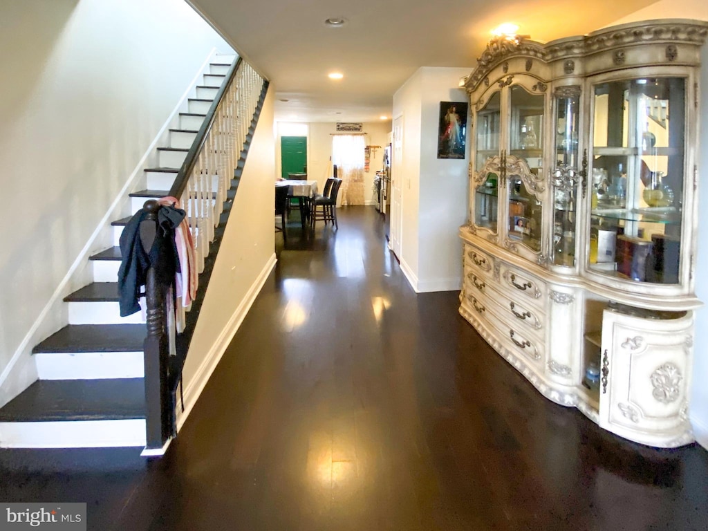 hallway with baseboards, recessed lighting, wood finished floors, and stairway