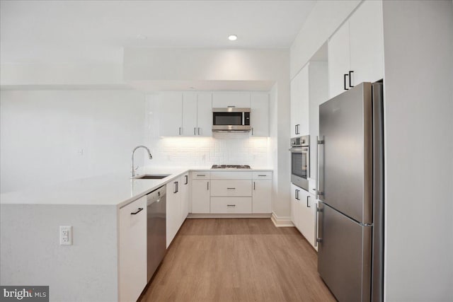923 V St NW Unit 602, Washington, DC 20001 - kitchen featuring stainless steel appliances, light wood-style flooring, tasteful backsplash, white cabinetry, and recessed lighting