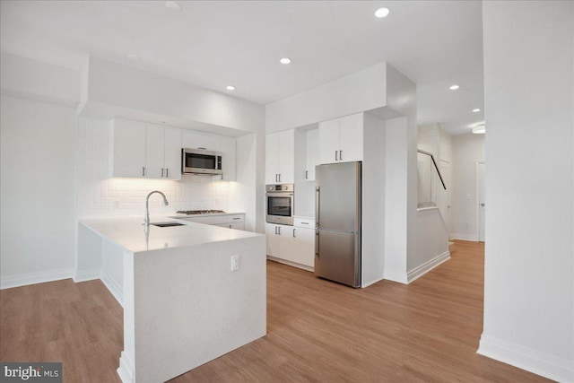 923 V St NW Unit 602, Washington, DC 20001 - kitchen featuring appliances with stainless steel finishes, a peninsula, white cabinets, light countertops, and backsplash