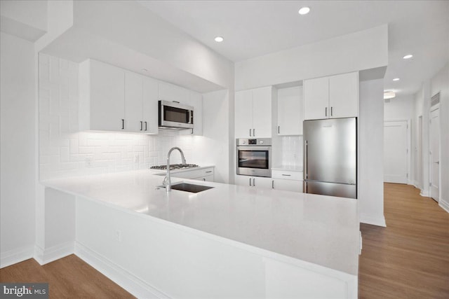 923 V St NW Unit 602, Washington, DC 20001 - kitchen featuring appliances with stainless steel finishes, a peninsula, light countertops, tasteful backsplash, and recessed lighting