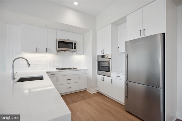 923 V St NW Unit 602, Washington, DC 20001 - kitchen with stainless steel appliances, light wood-type flooring, light countertops, backsplash, and white cabinets