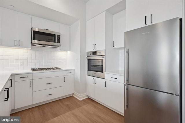 923 V St NW Unit 602, Washington, DC 20001 - kitchen with appliances with stainless steel finishes, light wood-style flooring, light countertops, backsplash, and white cabinets