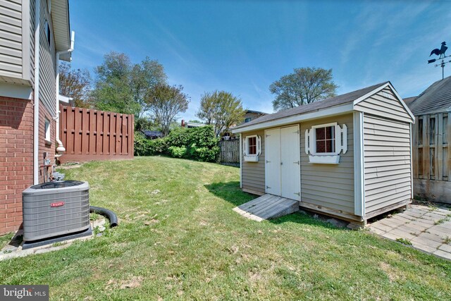 view of yard with an outdoor structure, fence, central AC unit, and a shed