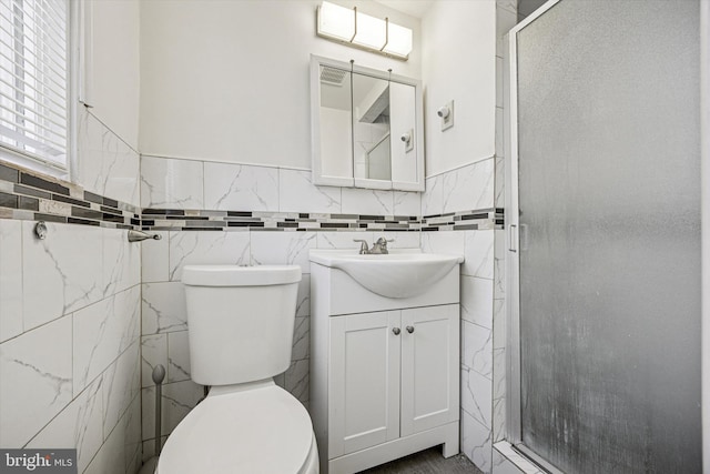 bathroom featuring vanity, toilet, tile walls, and a stall shower