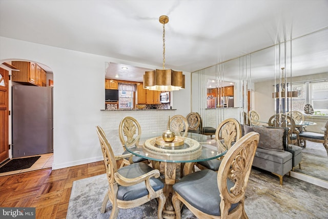 dining space featuring arched walkways and baseboards