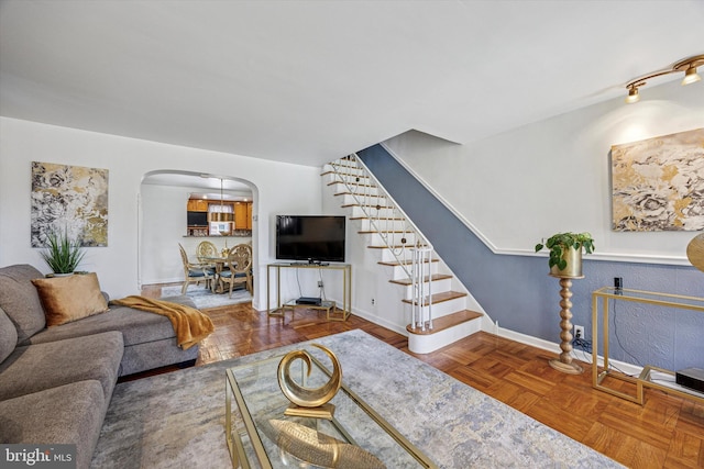living area with arched walkways, baseboards, and stairway