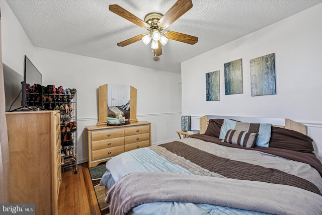 bedroom with a textured ceiling, ceiling fan, and wood finished floors