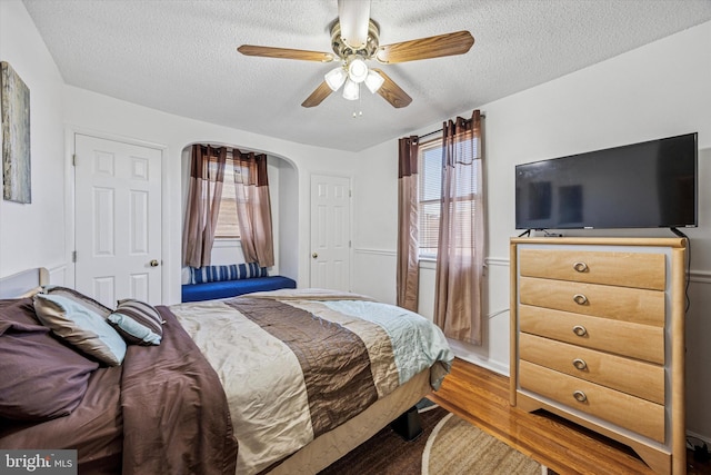 bedroom with a textured ceiling, wood finished floors, and multiple windows