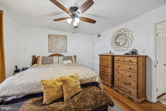 bedroom featuring a textured ceiling, ceiling fan, wood finished floors, and visible vents