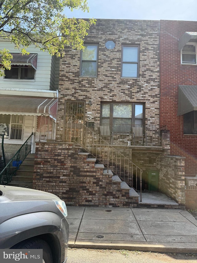 view of front of property featuring stairway and brick siding