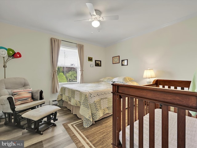 bedroom with crown molding, ceiling fan, wood finished floors, and baseboard heating