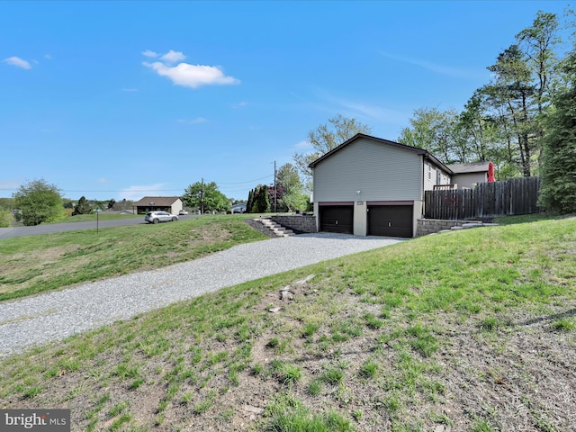 view of side of property featuring a garage, a yard, fence, and driveway