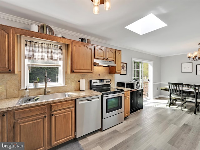 kitchen featuring a skylight, appliances with stainless steel finishes, a sink, an inviting chandelier, and ornamental molding