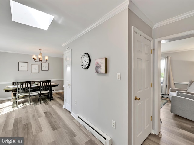 corridor with crown molding, a baseboard heating unit, a chandelier, light wood-style flooring, and a skylight