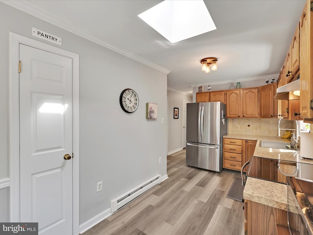 kitchen with crown molding, freestanding refrigerator, tasteful backsplash, a skylight, and a baseboard heating unit