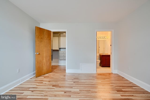 702 S Wolfe St Unit 5, Baltimore, MD 21231 - unfurnished bedroom with wood finished floors, baseboards, ensuite bathroom, and a spacious closet