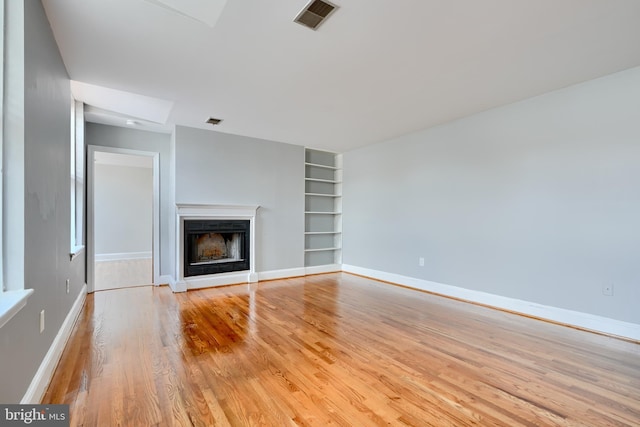 702 S Wolfe St Unit 5, Baltimore, MD 21231 - unfurnished living room with built in shelves, light wood-style flooring, a fireplace, and baseboards