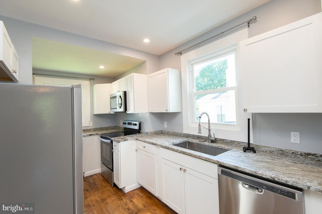 kitchen with appliances with stainless steel finishes, a sink, white cabinets, wood finished floors, and recessed lighting