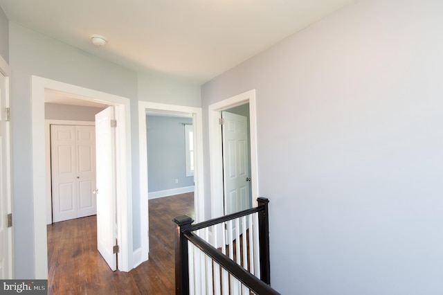corridor with an upstairs landing, dark wood finished floors, and baseboards