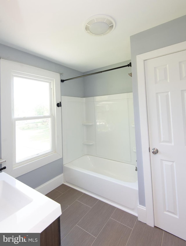 bathroom with baseboards, shower / bathtub combination, and wood tiled floors