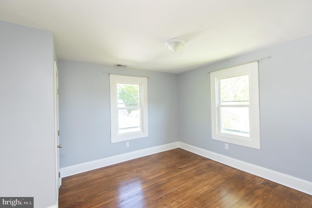 spare room with baseboards and dark wood-style floors