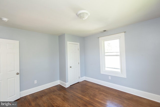 empty room featuring baseboards, dark wood-style floors, and a smoke detector