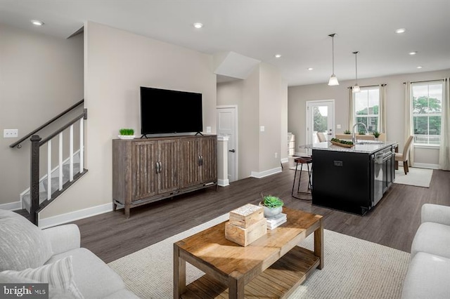 living room with stairs, baseboards, and dark wood-type flooring