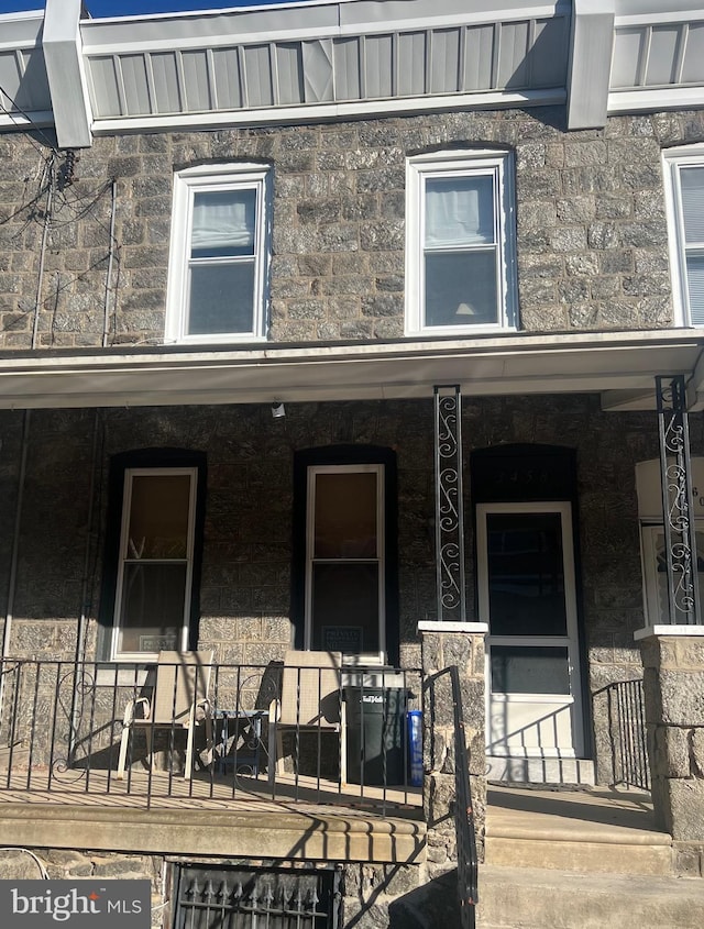 entrance to property with covered porch and stone siding