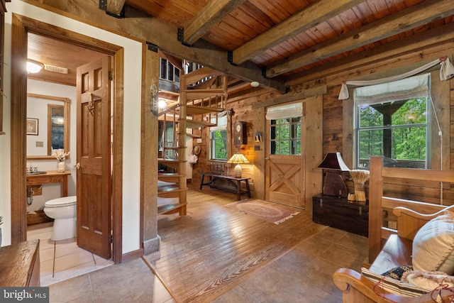 tiled living room featuring visible vents, wood walls, wooden ceiling, and beamed ceiling