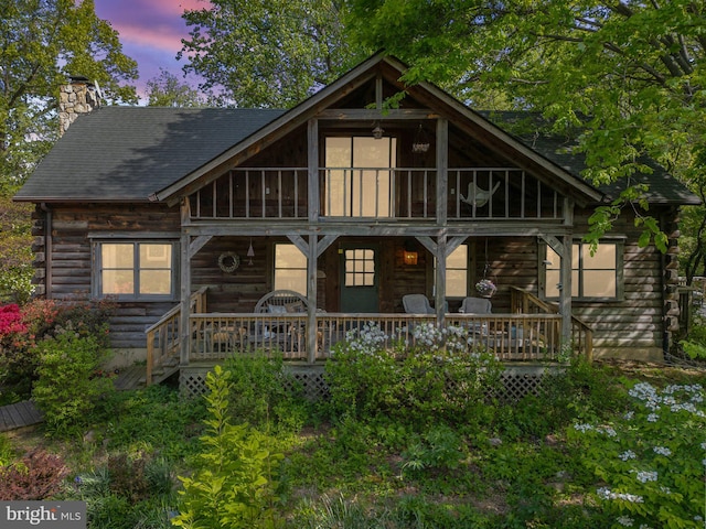 back of house featuring log exterior and a chimney