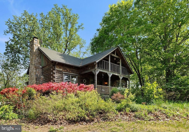 rear view of house with log exterior and a chimney